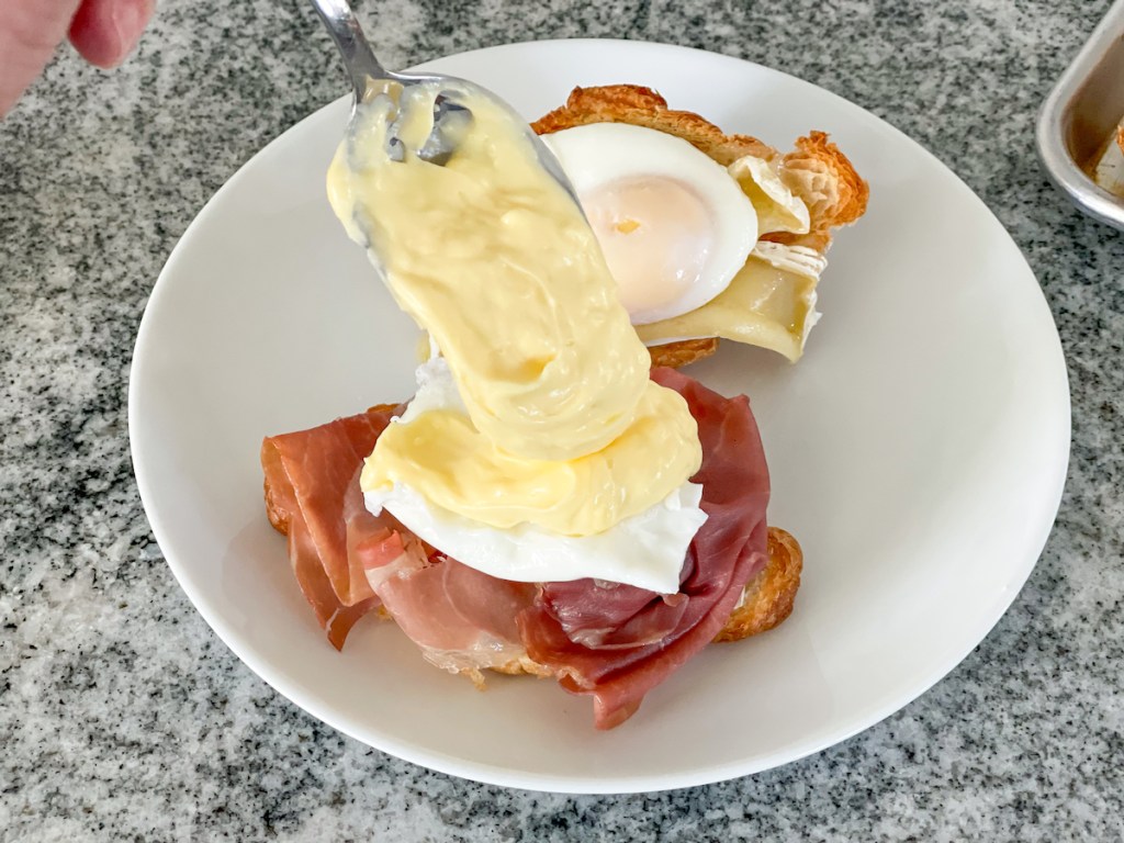 topping a keto eggs benedict with hollandaise sauce