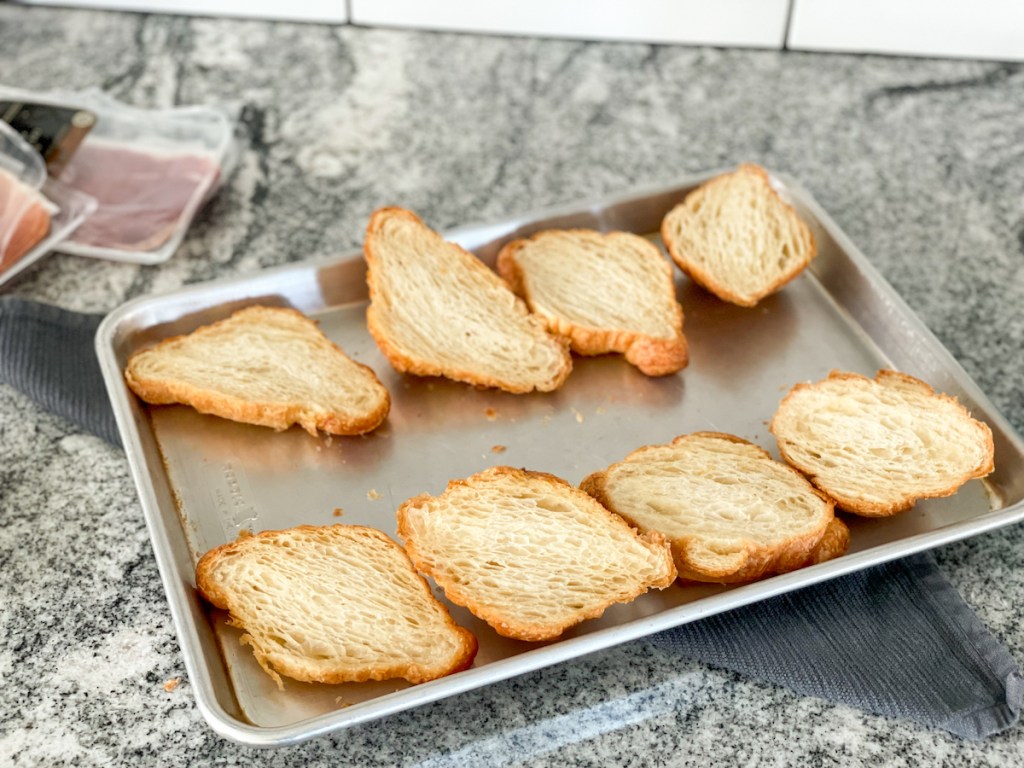 toasted hero bread croissants cut in half on a baking sheet