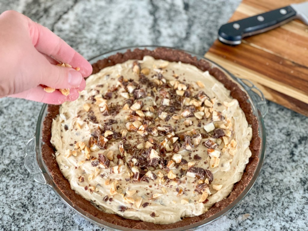 topping keto snickers pie with chopped peanuts and chopped up choczero rhea bar