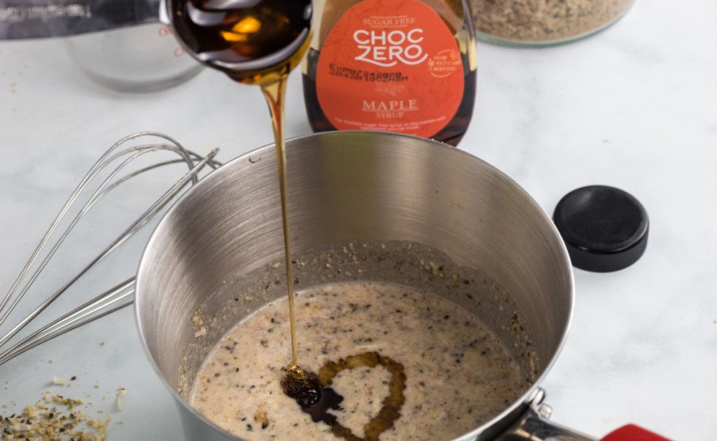 Pouring Choczero keto syrup into a mix of keto friendly oatmeal