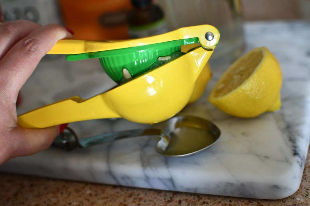 hand using a device to squeeze the juice out of a lemon