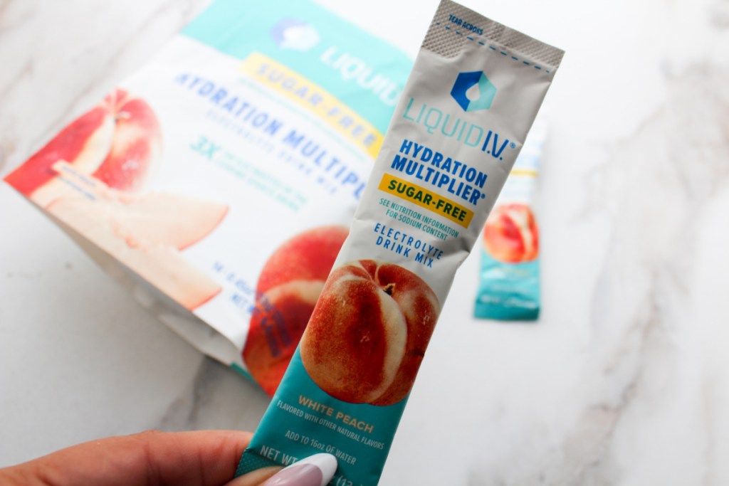 hand holding up a pack of sugar-free liquid IV in the flavor white peach