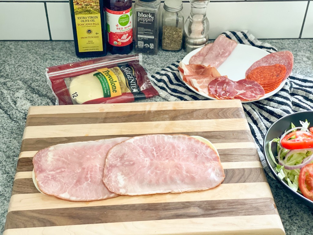 ham slices on top of provolone slices on a cutting board