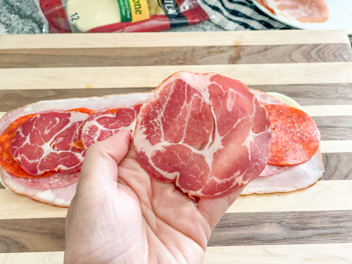 holding a slice of capocollo, an ingredient for our low carb Sub in a Tub Jersey Mike's copycat recipe