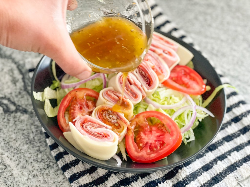 adding dressing to a salad sub in a tub