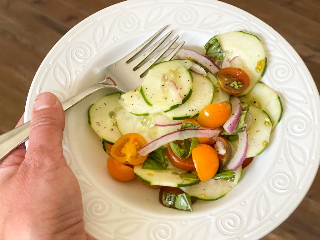 holding a bowl of keto cucumber salad