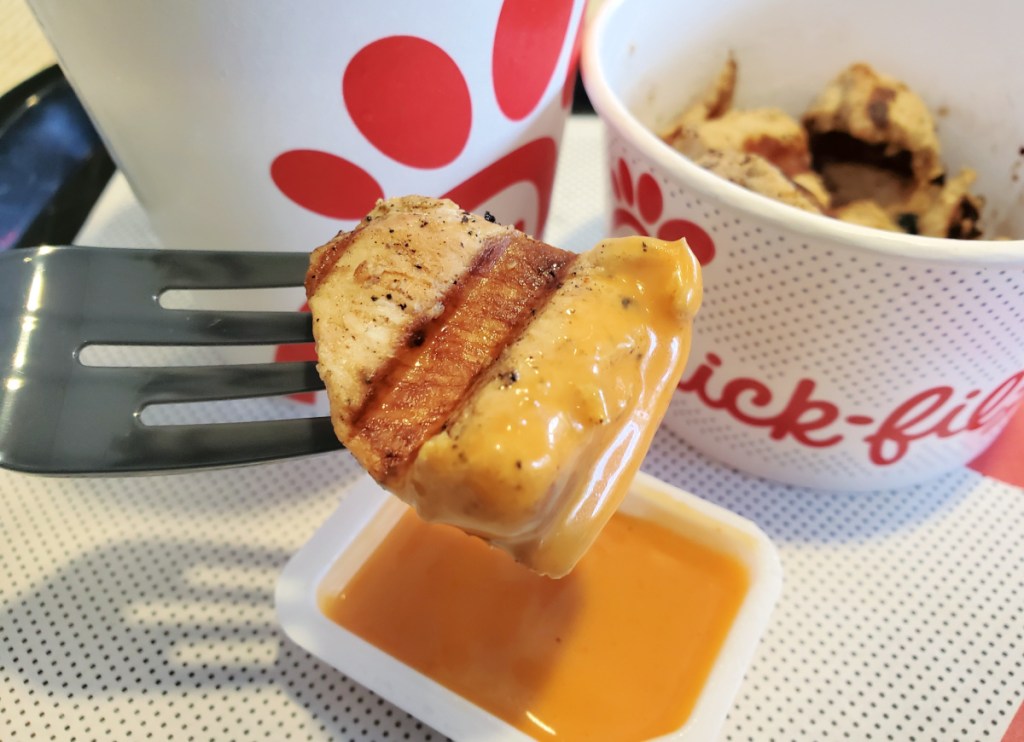 grilled chicken nugget being dipped into keto chick-fil-a sauce
