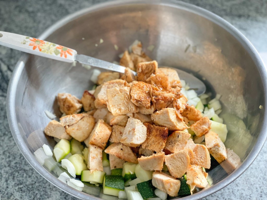 a bowl with chopped chicken, zucchini, and onion