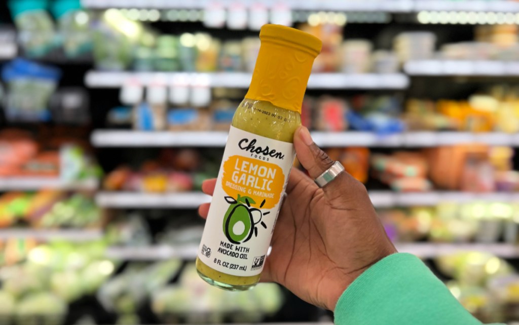 Hand holding a bottle of Chosen Foods Lemon Garlic Dressing which is a keto friendly salad dressing 