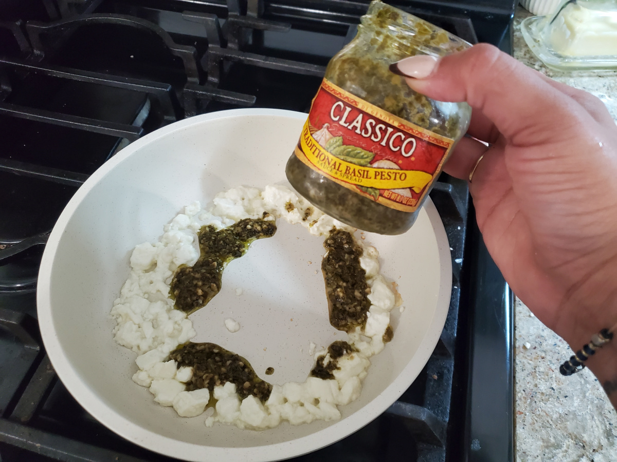 Putting pesto and feta in a skillet
