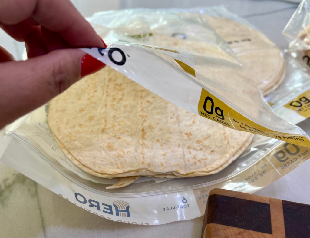 Hand opening up a package of hero tortillas