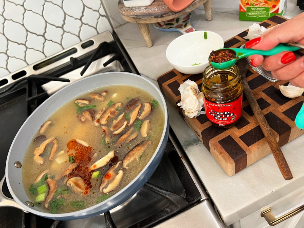 adding garlic chile sauce to hot and sour soup
