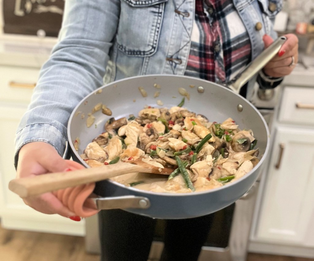 holding a keto skillet meal with chicken and cream sauce