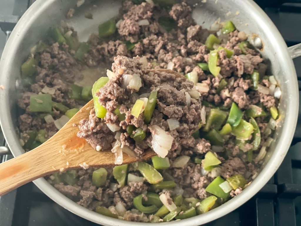 skillet with ground beef, green bell peppers, onions, and garlic