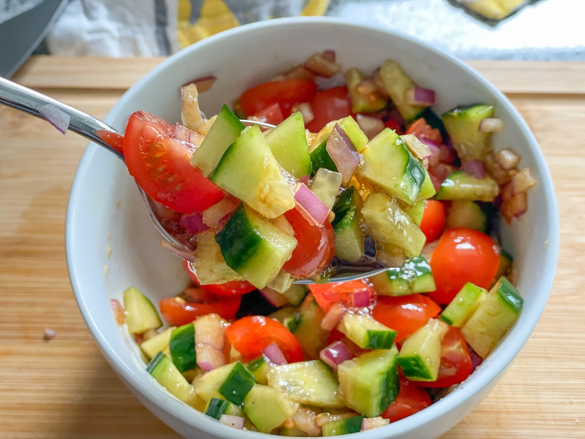 spoonful of chopped cucumber, tomatoes, and red onion with balsamic vinegar