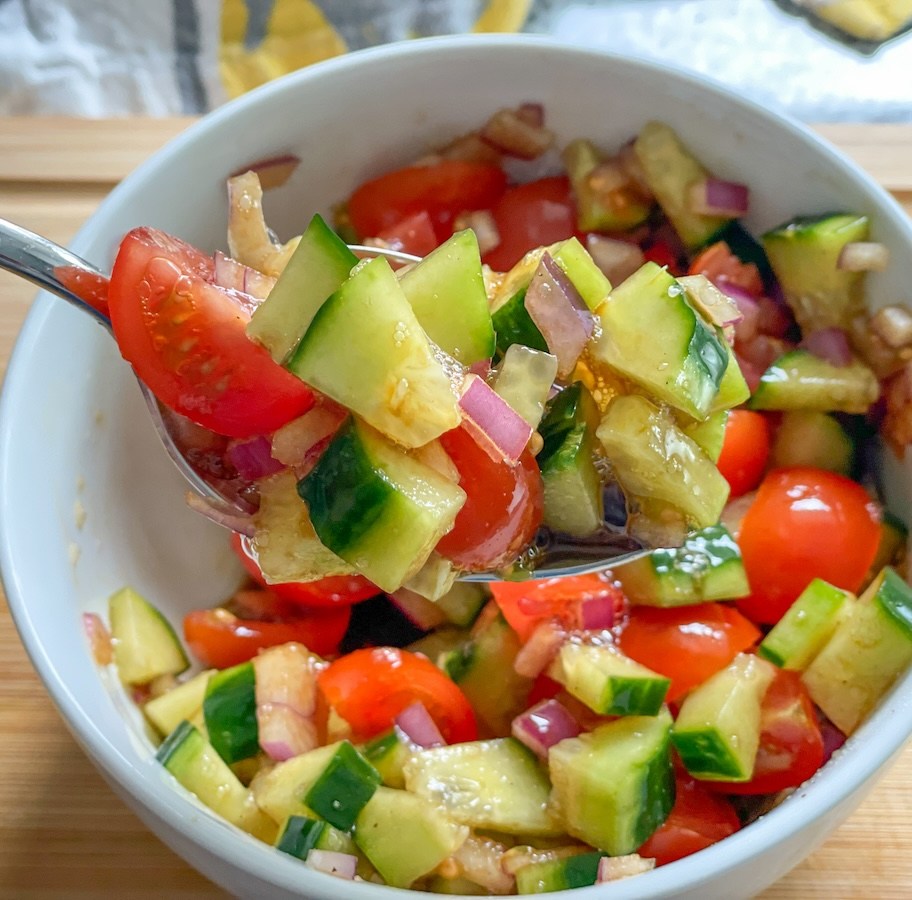 spoonful of chopped cucumber, tomatoes, and red onion with balsamic vinegar