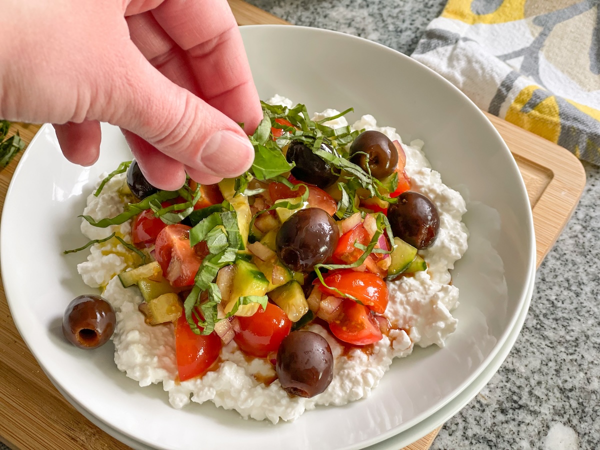 adding fresh basil to cottage cheese salad 