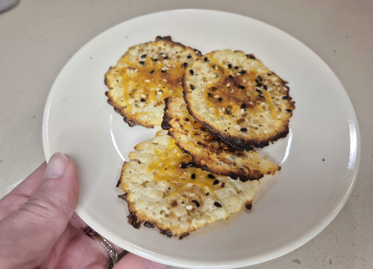 Hand holding a plate of baked cottage cheese chips