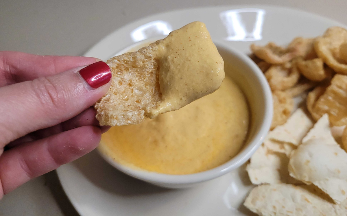 Pork Rind dipped in keto cottage cheese dip, similar to queso dip